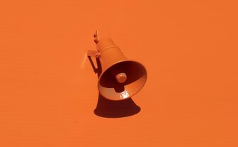 Ein orangenes Megaphon auf orangem Hintergrund.