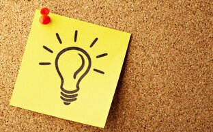 Notizzettel mit einer Glühlampe auf einem Kork Bord