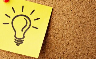 Notizzettel mit einer Glühlampe auf einem Kork Bord