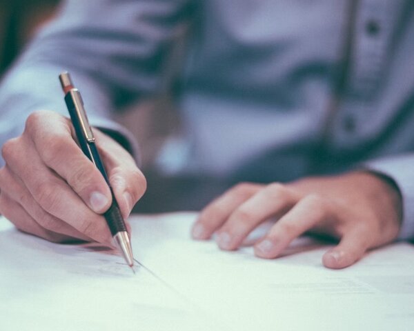 Ein Mann im Hemd unterschreibt ein Dokument