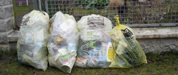 Gelbe Säcke stehen verschlosen am Wegrand vor dem Grundstück