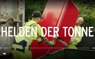 zwei Müllwerker beim Transport eines Kühlschranks