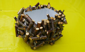 abgeschnittener Getränkekarton mit Aststücken beklebt