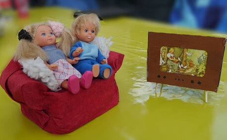 aus Abfällen gebasteltes Sofe mit Puppen und Fernseher