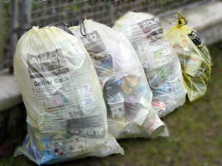 Gelbe Säcke stehen am Zaun