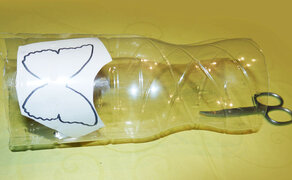 Zerschnittene Plastikflasche mit einer Schmetterlingsschnittvorlage darauf